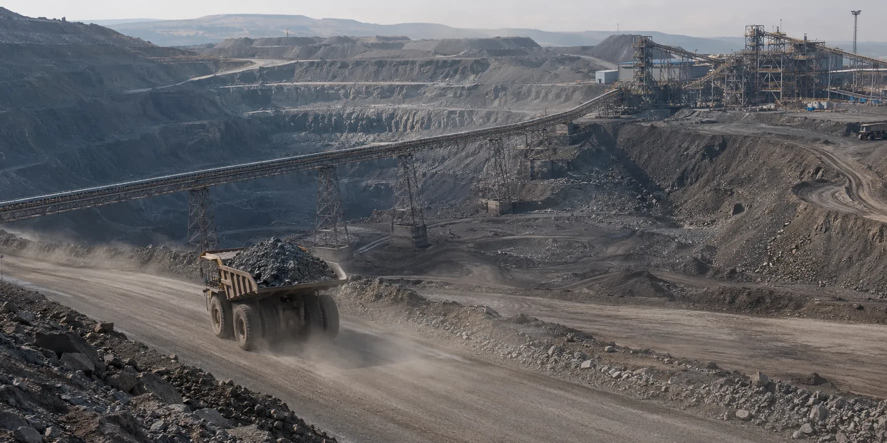 Open-pit mine with haul truck, terraced benches and processing infrastructure